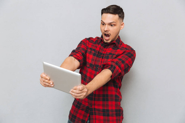 Шокированный человек играет на планшетном компьютере
 - Фото, изображение