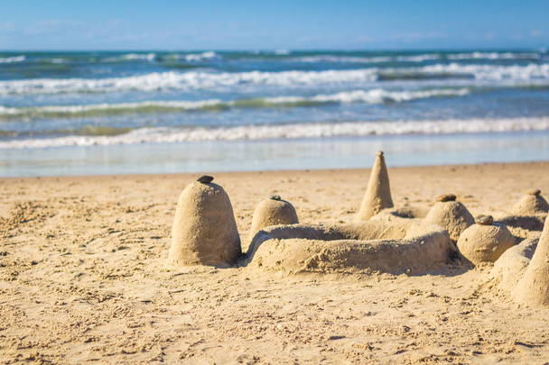 Sand castle on beach with rolling waves in background - Foto, Imagen