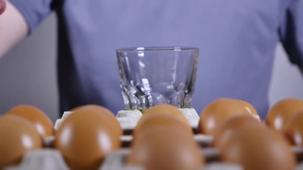 Mans hand breaks the egg into a glass, slow motion - Video, Çekim