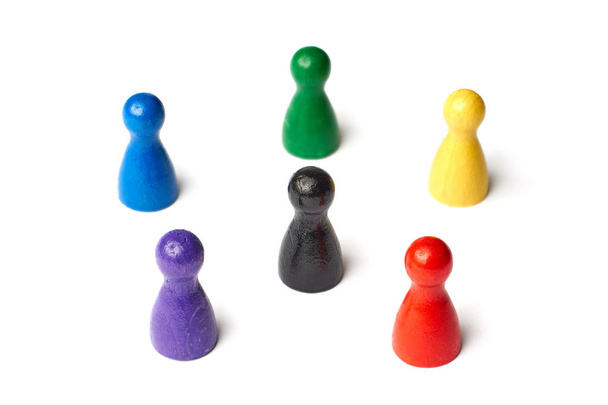 sechs Spielfiguren, die im Kreis stehen, mit einer schwarzen Figur in der Mitte. Symbol für ein Farbrad oder eine Gruppe von Menschen oder Teamwork. - Foto, Bild