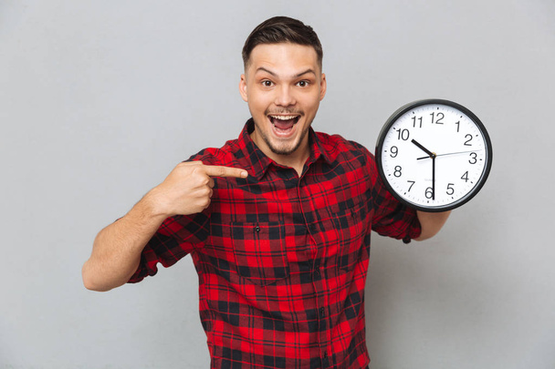 Happy man holding clock and pointing at their - Fotoğraf, Görsel