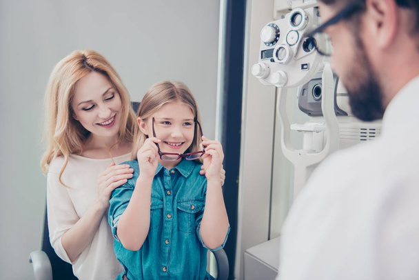 Small cheerful blond girl in jeans outfit is trying on glasses,  - Fotografie, Obrázek