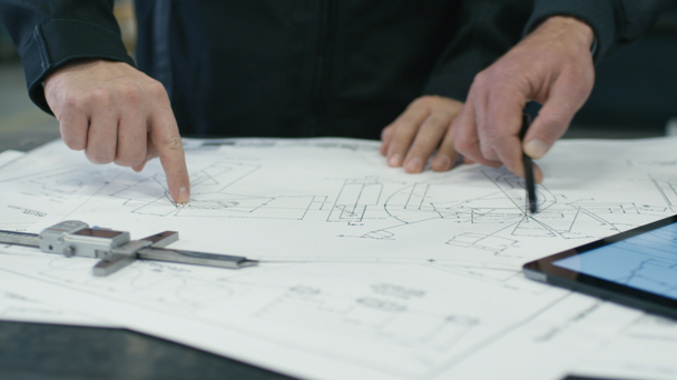 Közeli kép a két mérnököt megvitatni egy tervezetet a gyár. - Felvétel, videó