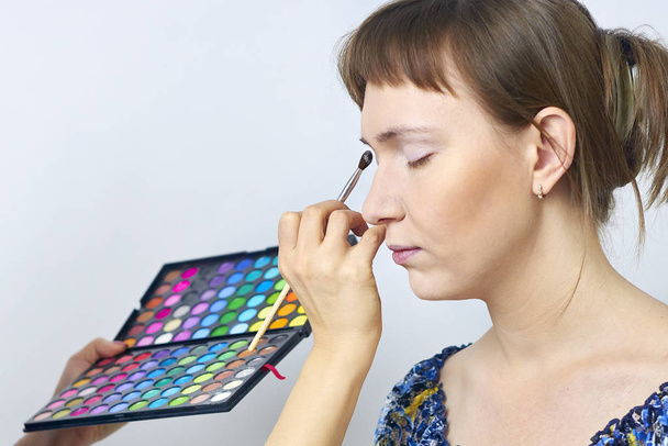 Vrouwelijke make-up model en visagiste hand met oogschaduw kwast en pallette - gecentreerd - Foto, afbeelding