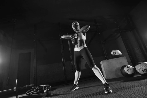 Muscular young fitness woman lifting a weight in the gym - Photo, image