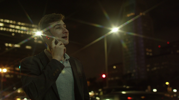 Vrolijke jonge toeristische er iemand belt via zijn smartphone op een straat - Video