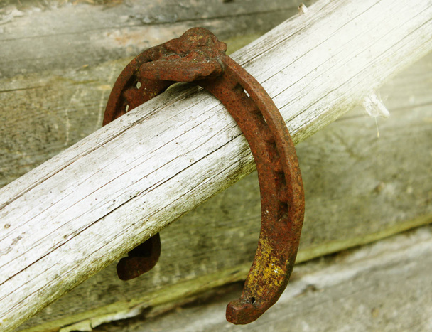 Античная ржавая подкова, закрепленная на ногтях на старой деревянной поверхности
 - Фото, изображение