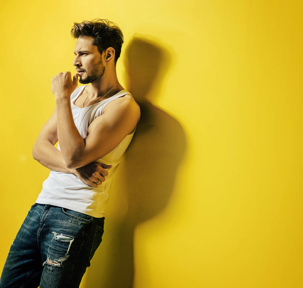 Handsome man leaning on the bright, yellow wall - Foto, Imagem