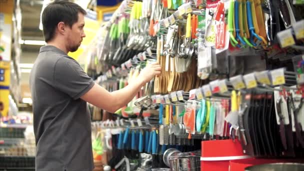 Male customer buying wooden spatula to his kitchen. He taking it from the shelf - Footage, Video