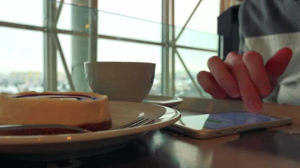 Un hombre con desayuno en una cafetería, trabaja en un smartphone
  - Metraje, vídeo