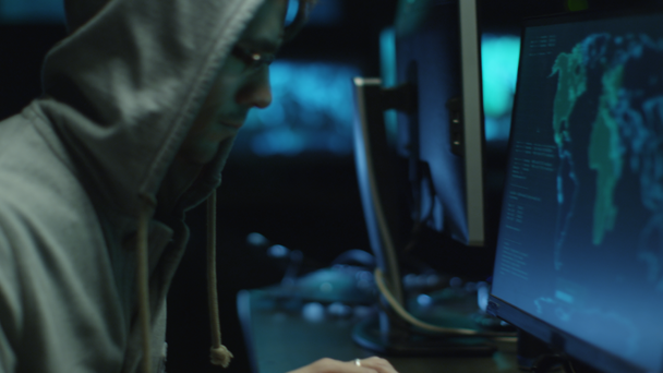 Δύο χάκερ σε κουκούλες δουλειά σε ένα υπολογιστές με χάρτες και τα δεδομένα στην οθόνη σε μια αίθουσα σκοτεινή γραφείου. - Πλάνα, βίντεο