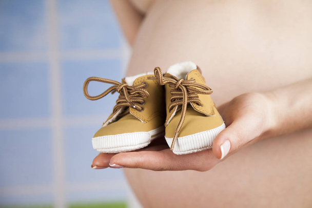 mujer embarazada sosteniendo zapatos de bebé  - Foto, imagen