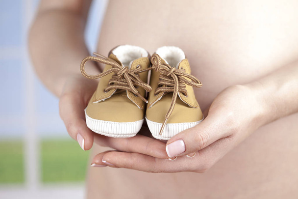 mulher grávida segurando sapatos de bebê - Foto, Imagem