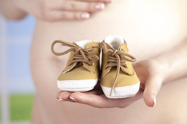 赤ちゃんの靴を持っている妊婦 - 写真・画像