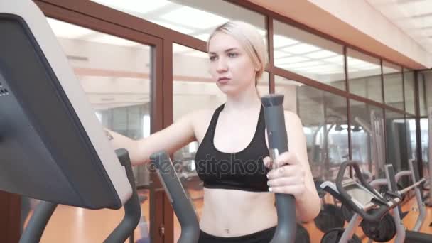 Young girl trains on an elliptical trainer in gym stock footage video - Video