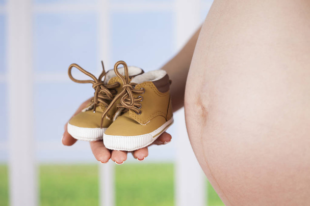 mujer embarazada sosteniendo zapatos de bebé - Foto, imagen