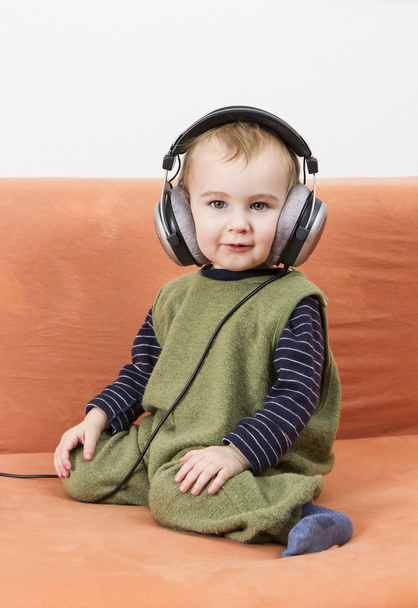 Young child on couch with headphone - 写真・画像