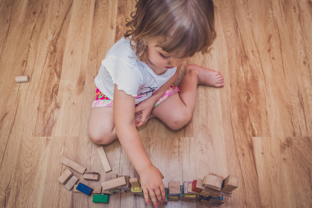 Girl playing with building blocks on floor - Foto, Bild