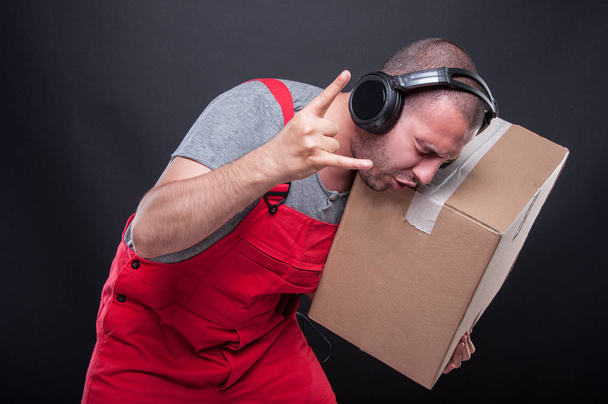 Μετακινούμενος τύπος κρατώντας κουτί χειρονομώ ροκ μουσική - Φωτογραφία, εικόνα