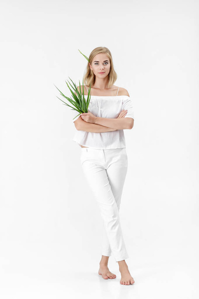 Beautiful blond woman in white blouse holding green onion on white background. Health and vitamins - Foto, Imagem