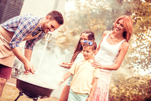Счастливая семья устраивает барбекю в саду
 - Фото, изображение