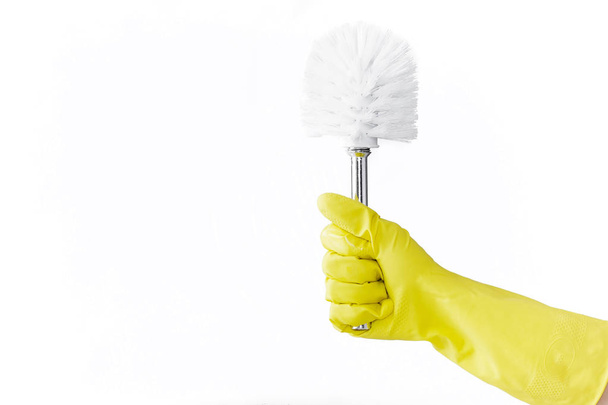 黄色のゴム手袋で手は、白い背景の上のトイレ用ブラシを保持しています。クリーニング. - 写真・画像