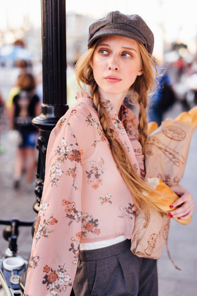 Young model stand on the street and hold bread with bike - Foto, imagen