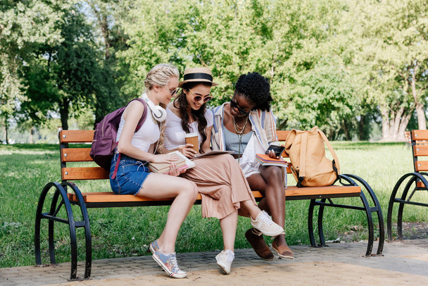 mujeres multiculturales utilizando tableta en el parque
 - Foto, imagen