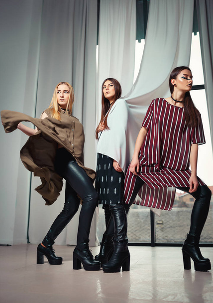 Three unique models with an unusual make-up and in original clothes posing on a podium - Photo, Image