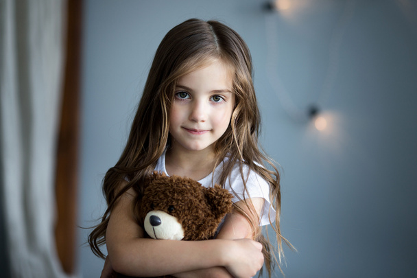 Portrait of a beautiful girl with a brown toy bear - Foto, afbeelding