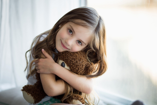 Portret van een mooi meisje met een speelgoed van de bruine beer - Foto, afbeelding