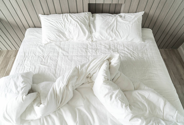 rumpled bed with white messy pillow decoration in bedroom  - Φωτογραφία, εικόνα