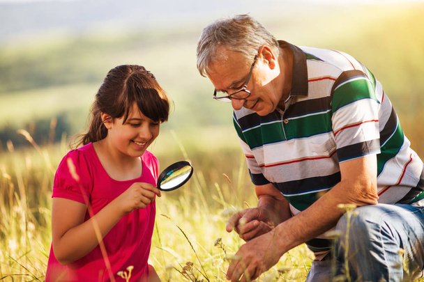 Grandfather and granddaughter explore nature with magnifying glass - Fotografie, Obrázek