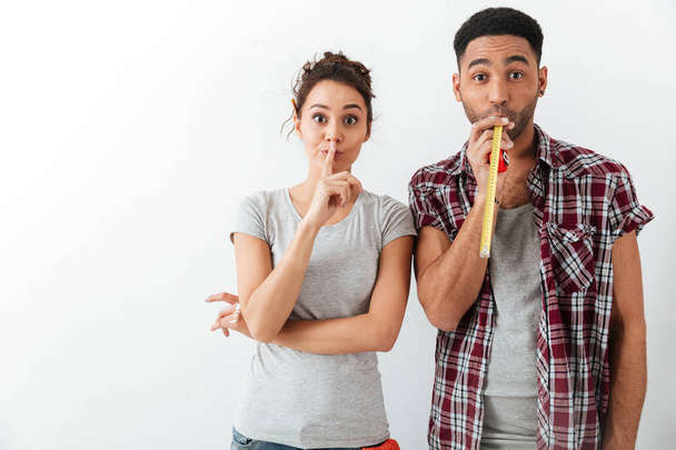 Funny young couple showing silence gesture and using measuring tape - Foto, afbeelding