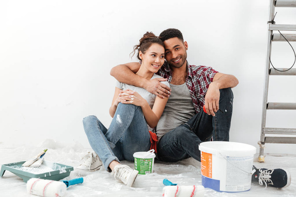 Happy multiethnic young couple renovating home and hugging - Foto, afbeelding