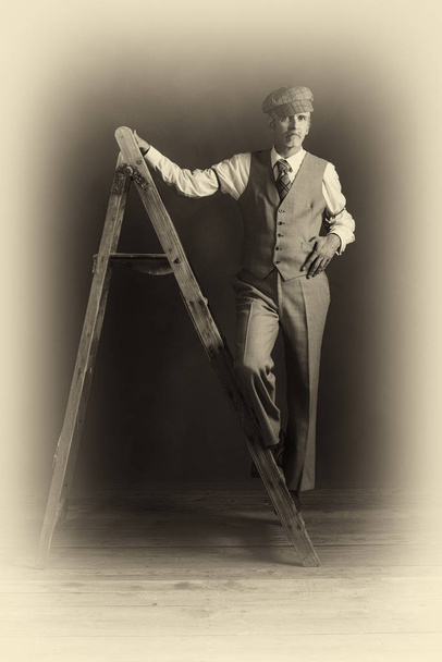 ο άνθρωπος στο κοστούμι στέκεται πάνω σε ξύλινη σκάλα - Φωτογραφία, εικόνα
