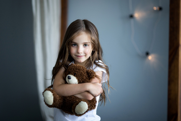 Portréja egy gyönyörű lány, egy barna-játék medve - Fotó, kép