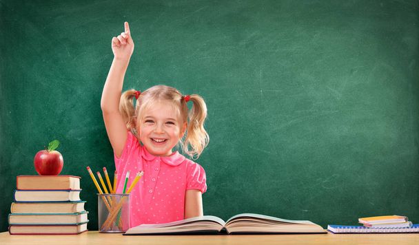 Menina feliz levantando a mão na sala de aula
 - Foto, Imagem