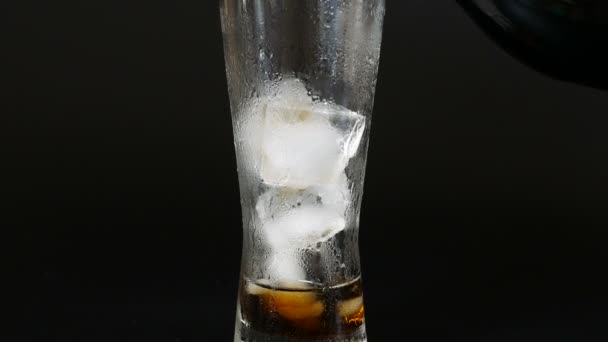 Giet de cola uit een plastic fles in een glazen van ijs - Video