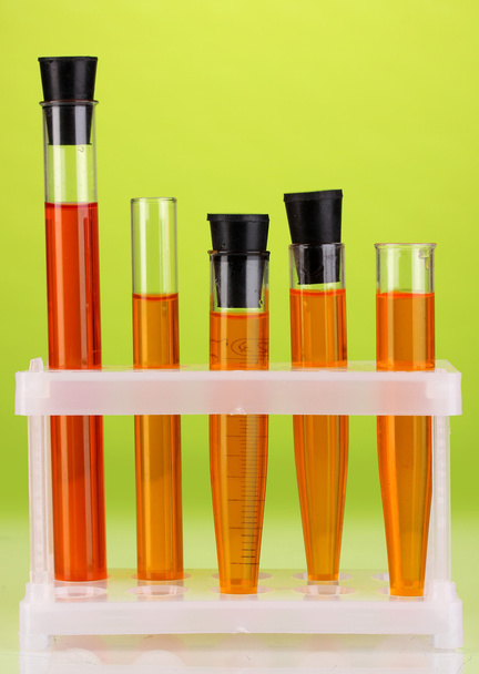 Test-tubes with a colorful solution on green background close-up - Foto, Imagem