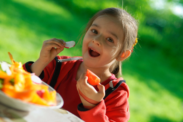 Mädchen isst Tomate und Gartenrettich - Foto, Bild