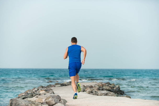 Giovane atleta vista posteriore corridore che corre lungo la spiaggia
 - Foto, immagini