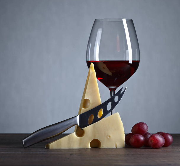 Cheese and red wine on a old wooden table - Foto, afbeelding