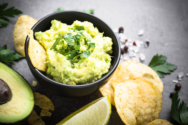 Traditional latinamerican mexican sauce guacamole and chips on b - 写真・画像