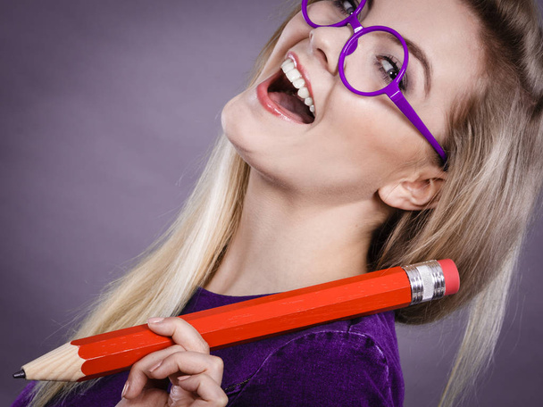 Smiling woman holds big pencil in hand - Foto, imagen