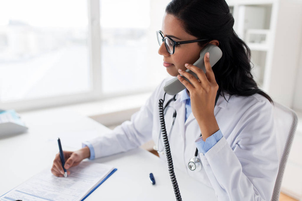 doctor with clipboard calling on phone at hospital - Valokuva, kuva