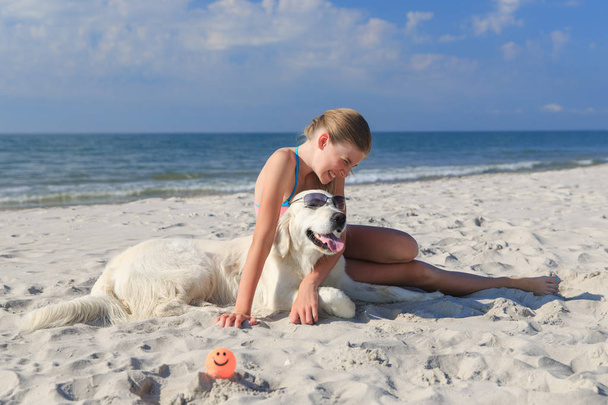 happy girl playing with a dog on the beach - Foto, Bild