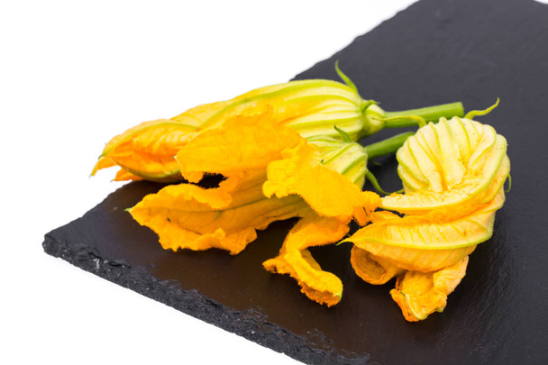 Flores de calabaza amarillas y calabacín sobre negro
 - Foto, Imagen