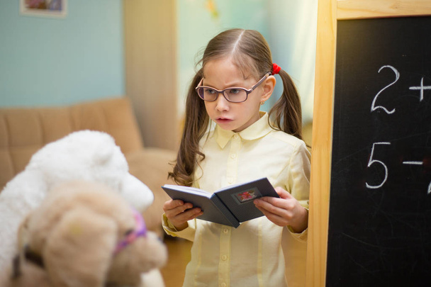 Little teacher in glasses. Beautiful young girl is teaching toys - Photo, Image