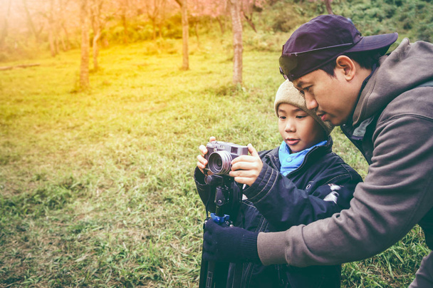 Familia feliz. Padre enseñando a su hijo fotografiando al aire libre en el bosque
. - Foto, Imagen